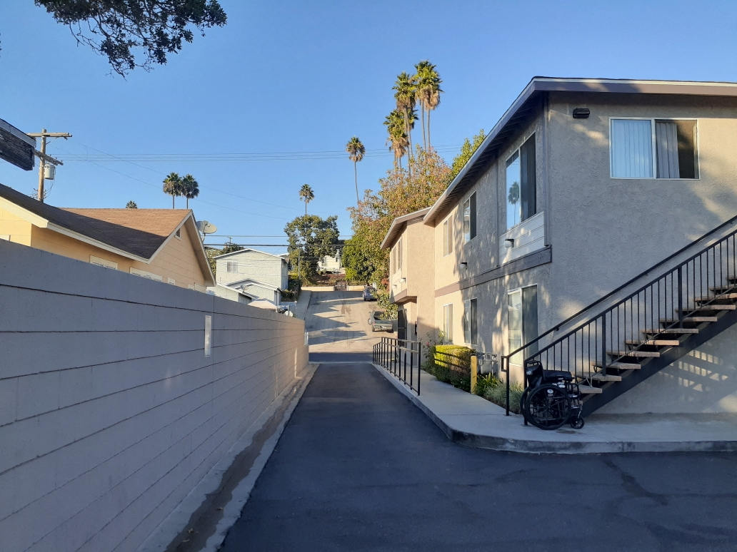 A residential street with houses on both sides and a clear blue sky.